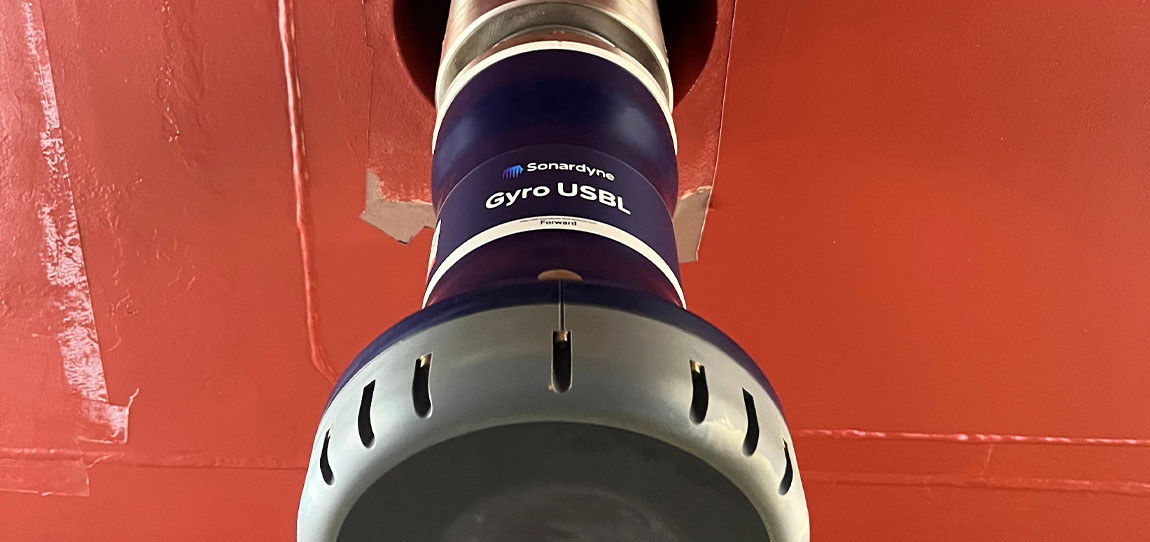 A Sonardyne Gyro USBL device, dark blue and gray, extends from a red hull. The device has 'Sonardyne Gyro USBL' written on it.