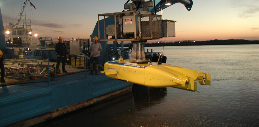 A Maridan AUV being launched over the side of a ship in calm waters.