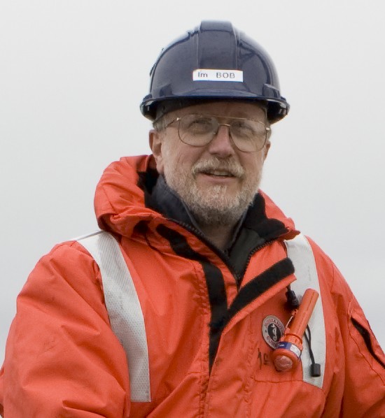 A man named Bob in a blue hard hat and orange safety jacket with reflective stripes.