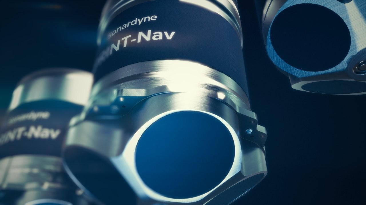 Close-up of three Sonardyne INT-Nav cylindrical devices with metallic and dark blue components, featuring circular sensor openings.